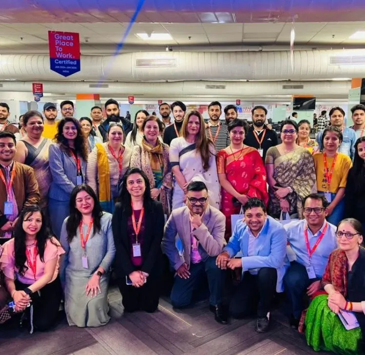 Shefali Chopra at the centre of a large corporate team photo in an office