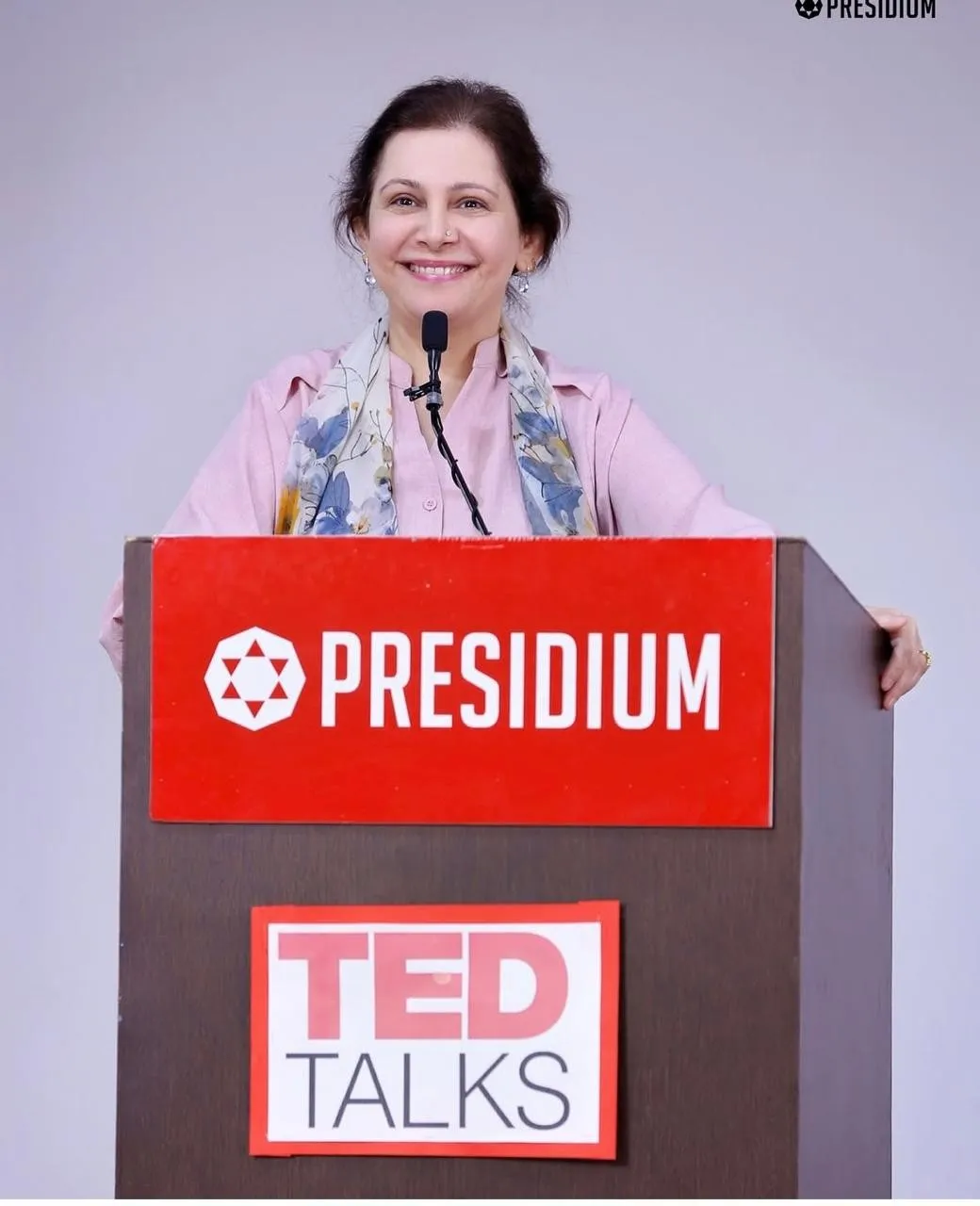 Shefali Chopra smiling at a Presidium podium with a TED Talks sign