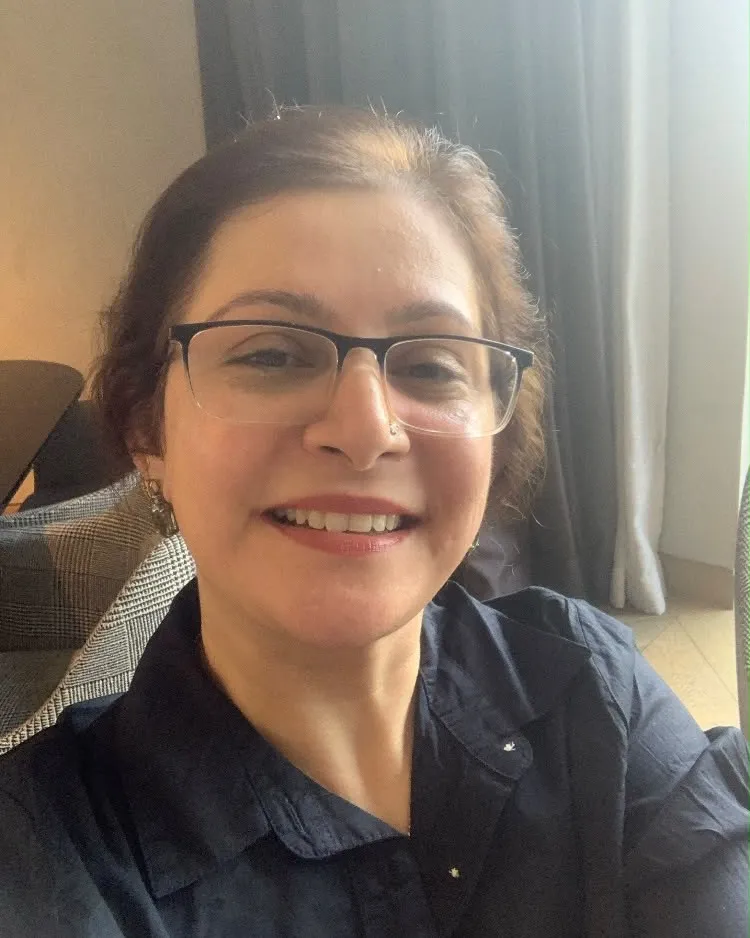 Shefali Chopra smiling, in glasses and a navy shirt