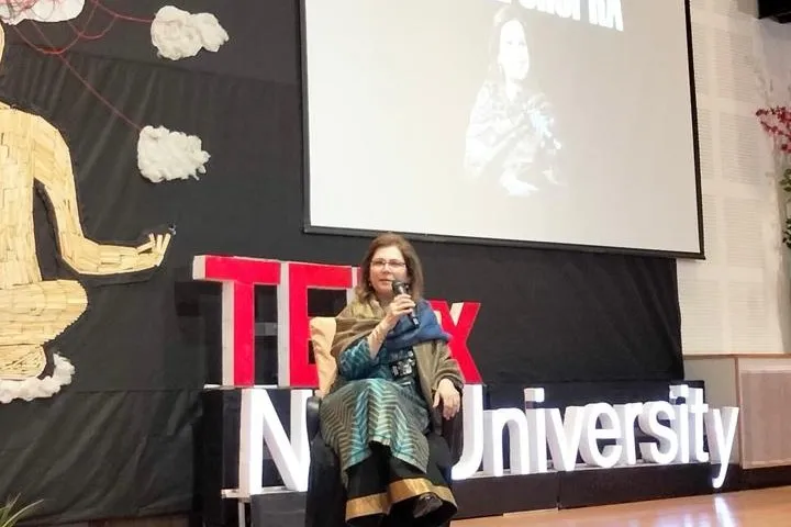 Shefali Chopra on stage at TEDxNIIT University, her name on the screen behind her